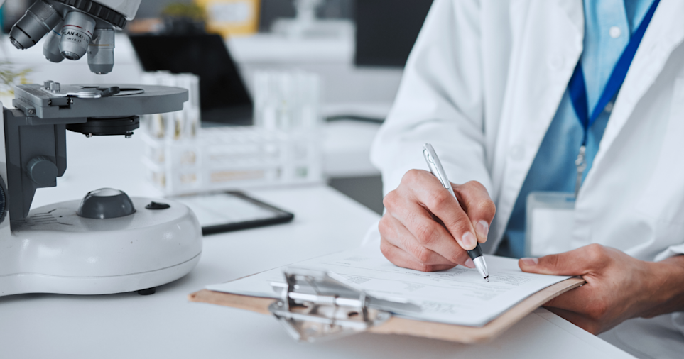 A man in a white coat and lanyard writes on a clip board, next to a microscope. A lab setting is blurred in the background. Stats on top are: 5.9% increase in email opt-ins, 63% lift in open rate, and 20 hours saved per month.

