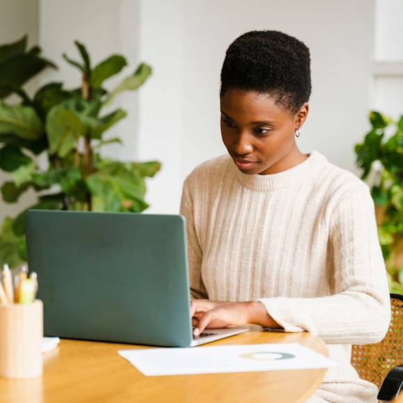 Person in white sweater working on laptop