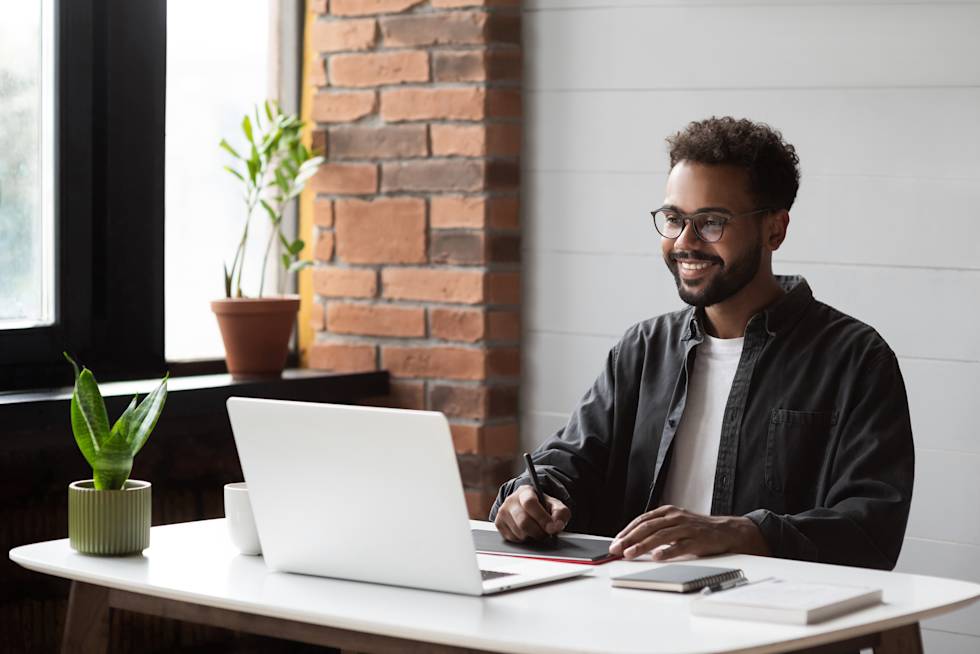 A person smiling while working on their laptop.