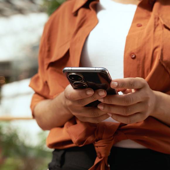Person with orange shirt using phone