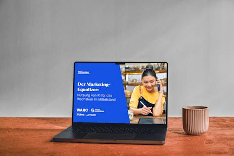 Laptop mit dem Whitepaper „The Marketing Equalizer“ auf blauem Hintergrund, mit Keramikschalen auf einer Holzoberfläche