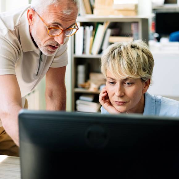Man instructing a coworker on the computer