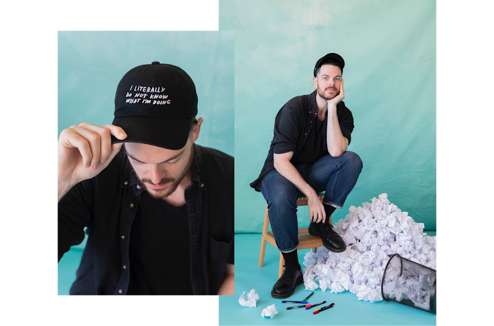 Adam Kurtz wearing a hat with his art and sitting on a stool next to tossed ideas.