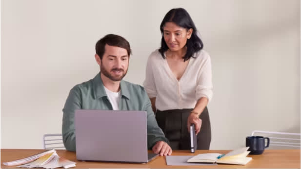 A professional shares information on a laptop with a colleague. 