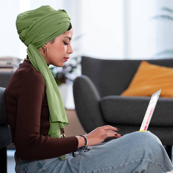 Woman sitting in a chair, typing on a laptop