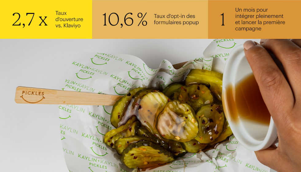 Cornichons arrosés de sauce blanche sur du papier marqué d’un logo représentant un smiley vert et accompagnés d’une fourchette en bois