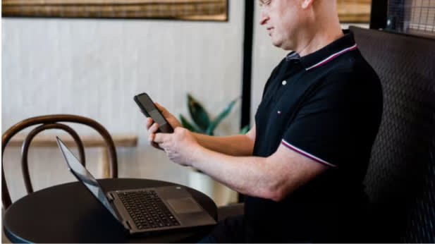 A professional man working at a table with a laptop and mobile phone.