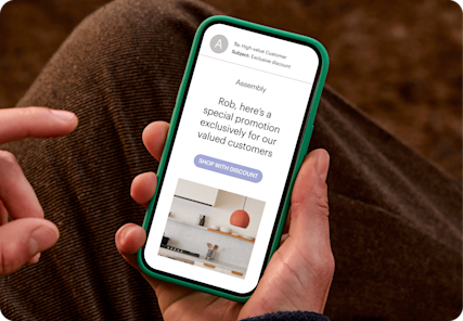 Image of a person looking at a smartphone screen displaying an email from the fictitious brand Assembly. The visual demonstrates how users can personalize marketing campaigns with segments based on customer data.