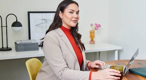 Woman in blazer working on laptop