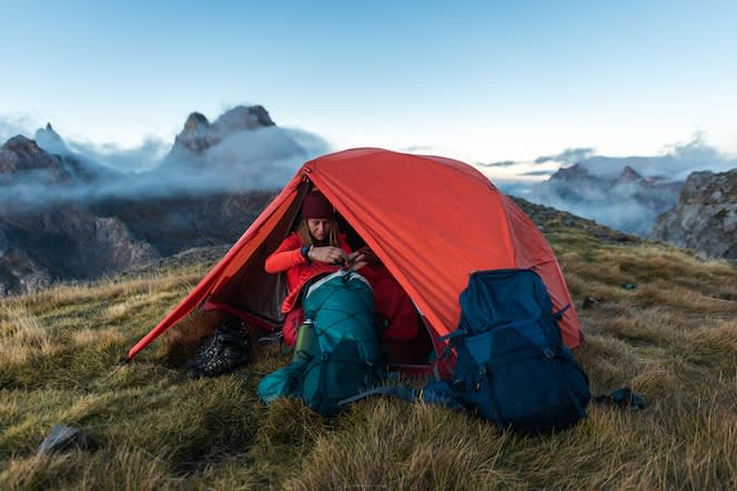 Woman camping in a red tent on a mountain