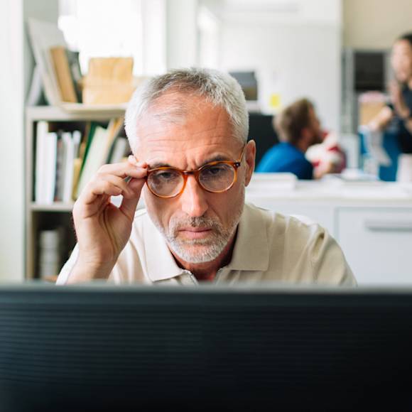 Man with glasses looking at a screen