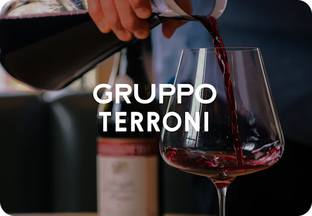 A Gruppo Terroni restaurant wine bottle and serving glass pouring wine into a wine glass.