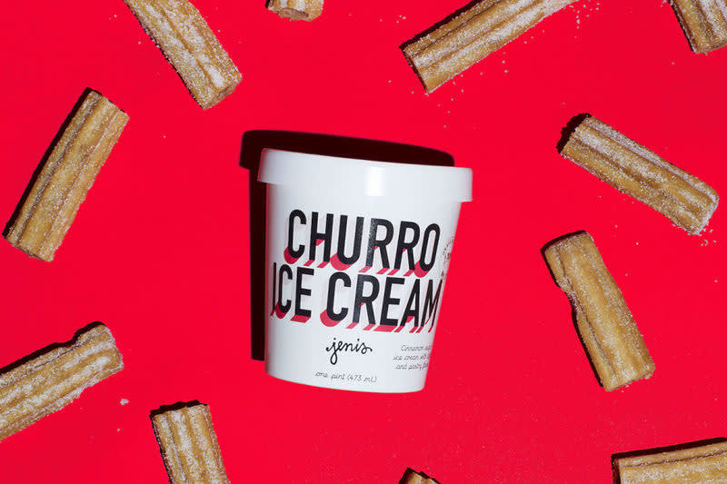 White ice cream container labeled "Churro Ice Cream" surrounded by churro pieces on bright red background