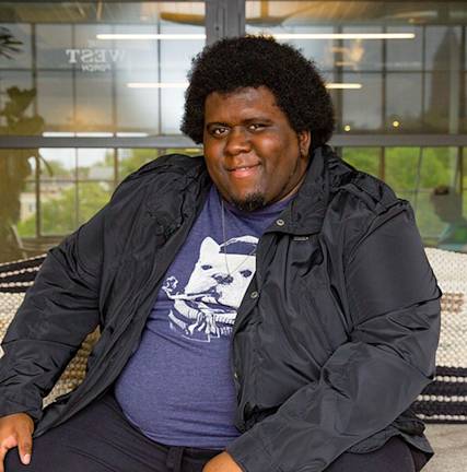 A photo of Maurice Cherry sitting in front of a window.