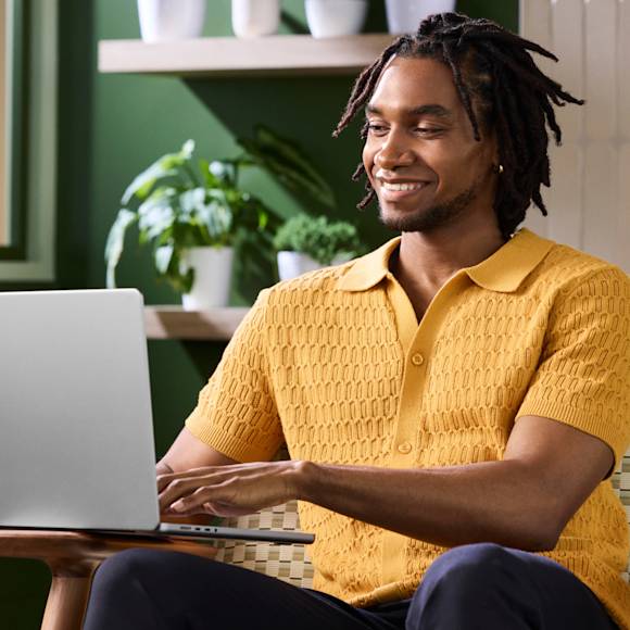 Man in yellow polo, typing on a laptop