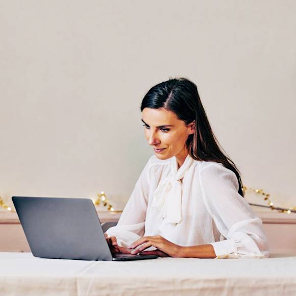 Woman in white shirt, working on a laptop