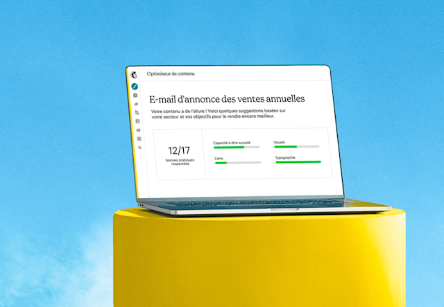 Ordinateur portable ouvert sur une plate-forme jaune sur fond de ciel bleu affichant à l'écran le créateur de segments avancés de Mailchimp