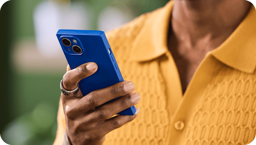 Image of a person looking at a smartphone. The visual suggests how users can learn from Mailchimp’s Text message marketing guide.