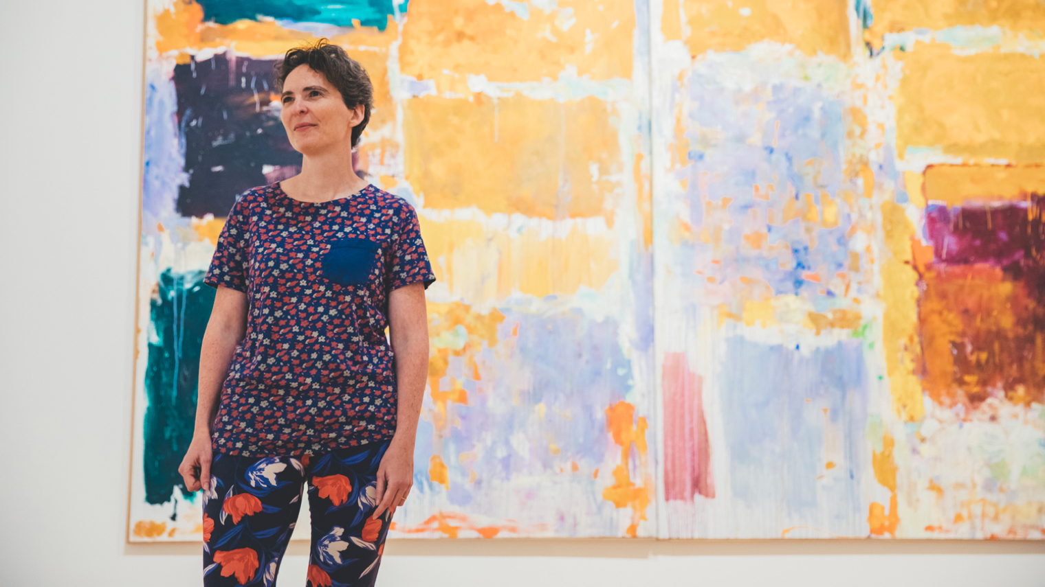 Hillary Brown stands in front of a large painting. 