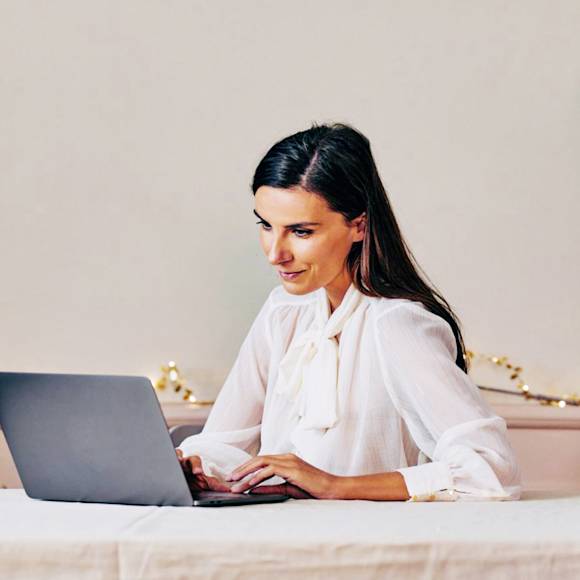 Woman in white shirt, working on laptop