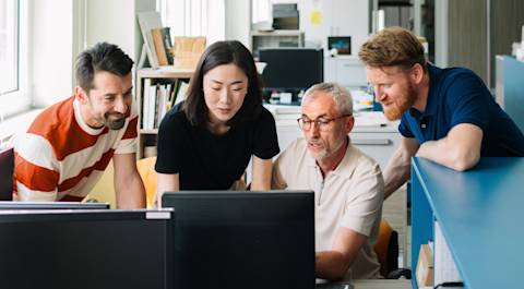 Team gathers around computer screen