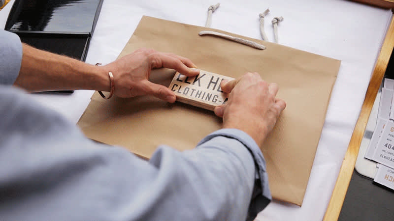 A person stamping the Elk Head logo onto a bag