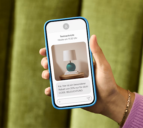 Eine Hand, die ein Smartphone zeigt, das gerade eine Marketing-Textnachricht erhalten hat: „Alex, hier ist ein spezieller Rabatt von 20 % nur für dich!“ CODE: BELEUCHTUNG“
