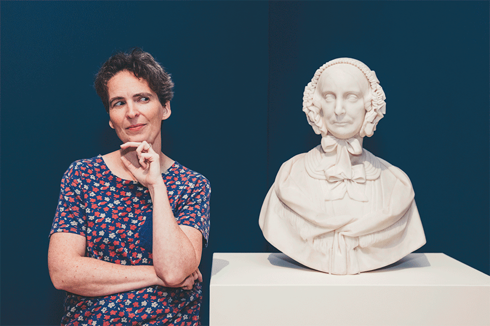 Hilary Brown winks at statue bust.