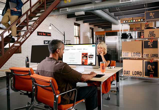 Modern industrial office space with exposed brick walls, orange chairs, and Oat Lord branding signs displayed throughout