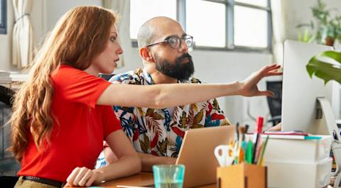 Woman in a red shirt, working with a co-worker