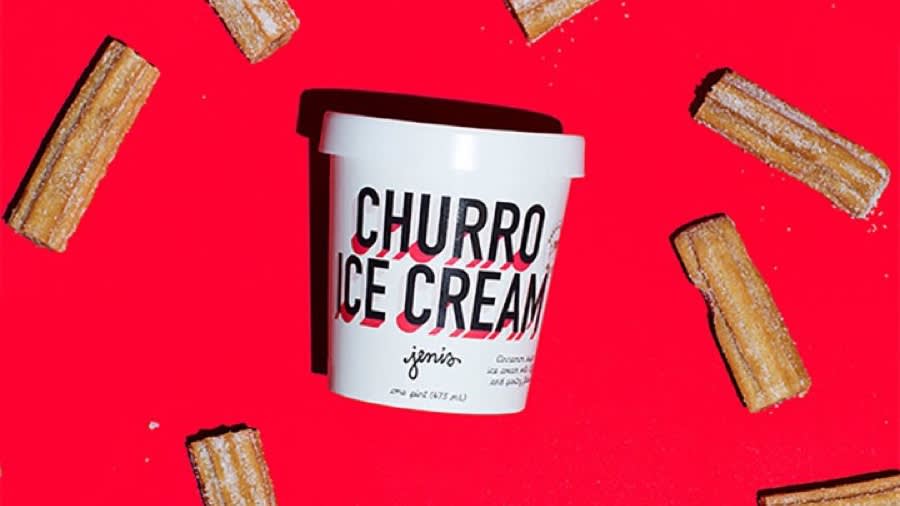 White pint container of Churro Ice Cream surrounded by churro pieces on bright red background