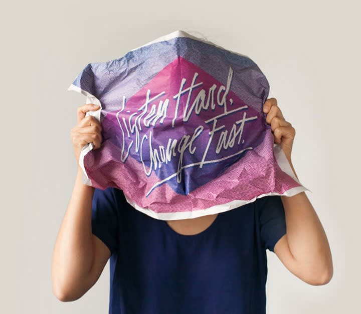Hands holding up a pink and purple tie-dye fabric with cursive text "Safety Hard, Change Fast" against a light gray background