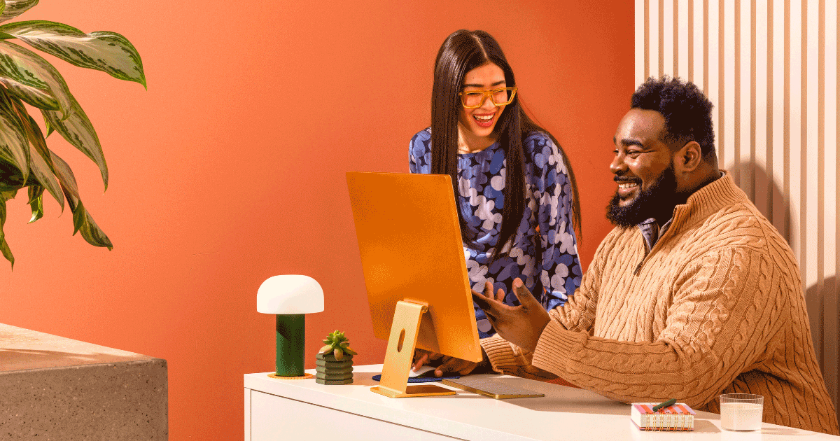 Two cheerful colleagues looking at a computer screen.