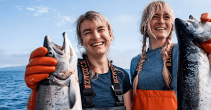 Image of Intuit Mailchimp Customer Salmon Sisters smiling while each holding a fish out in front of them