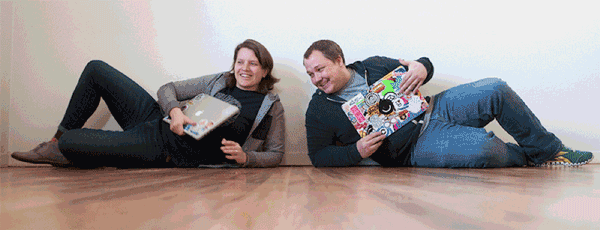 Two people lying on wooden floor reading magazines side by side, relaxing casually in comfortable poses