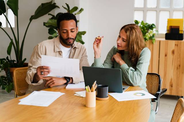 Coworkers collaborate with laptop and papers