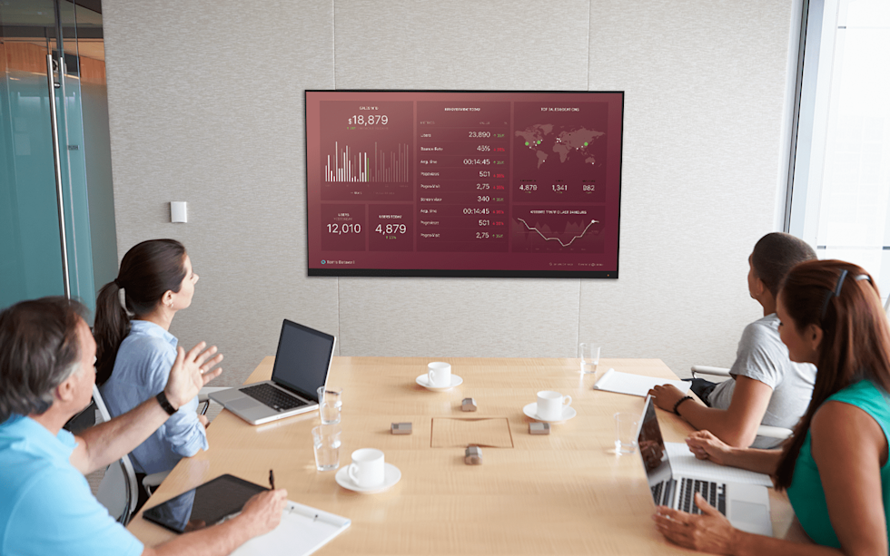 Image of people at a table looking at a screen with different charts on it 