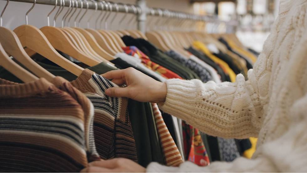 Photo of Corina looking through sweaters hanging on display.
