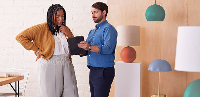 Business professionals having an animated discussion in a modern office space with turquoise pendant lights and beige walls
