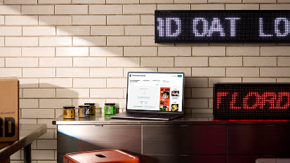 Interior view of a modern restaurant with white brick walls, LED signage, and counter service area under dim lighting