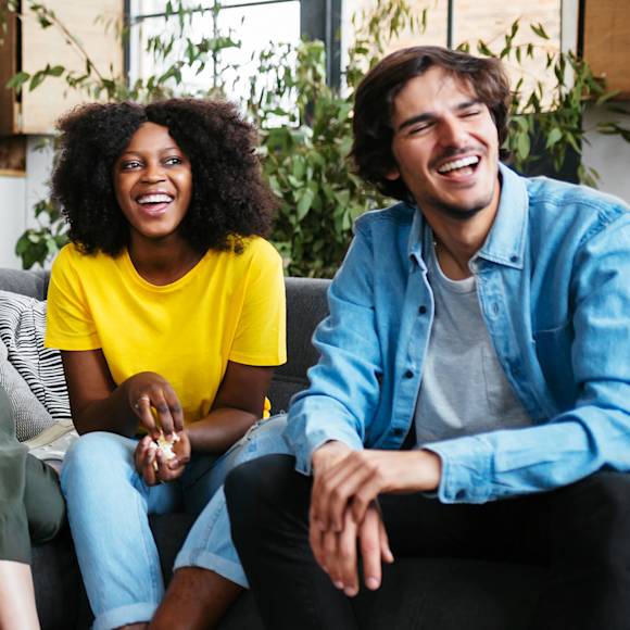 Two people sitting on a couch and laughing