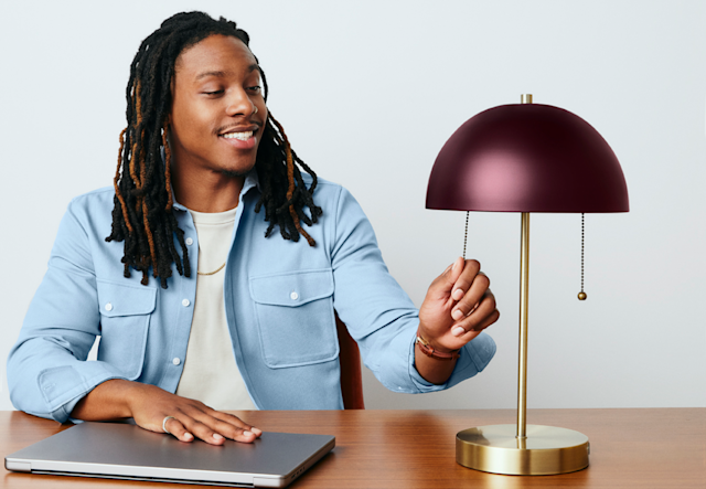 Man with laptop turning on a lamp