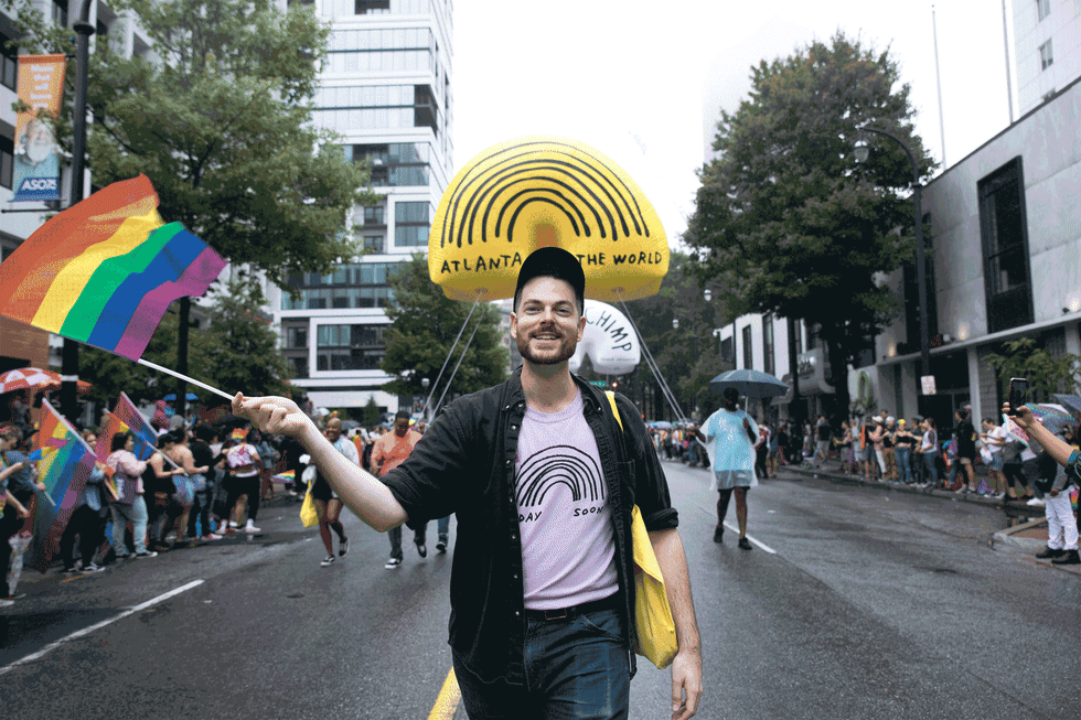 Adam Kurtz waving a pride flag while walking in the Atlanta Pride Parade with Mailchimp.