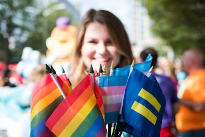 Small rainbow pride flags and transgender flag on display at outdoor LGBTQ+ celebration with blurred festive background
